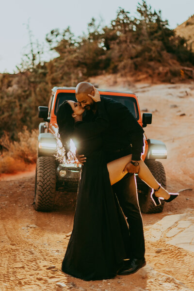 man and woman in black pose in front of jeep for engagement photos in sedona