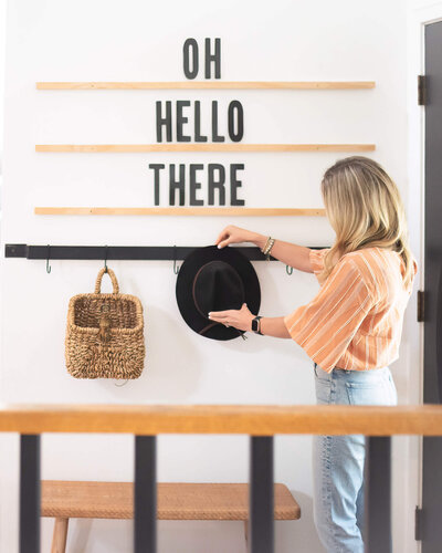 woman staging a hat on a hook in an entryway