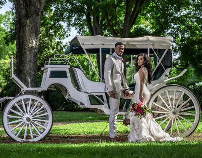 wedding couple in front of horse carriage with red flowers