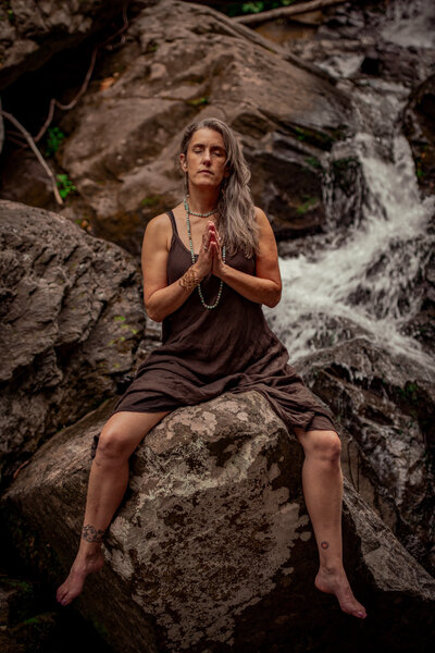 Woman meditating by waterfall during spiritual practice