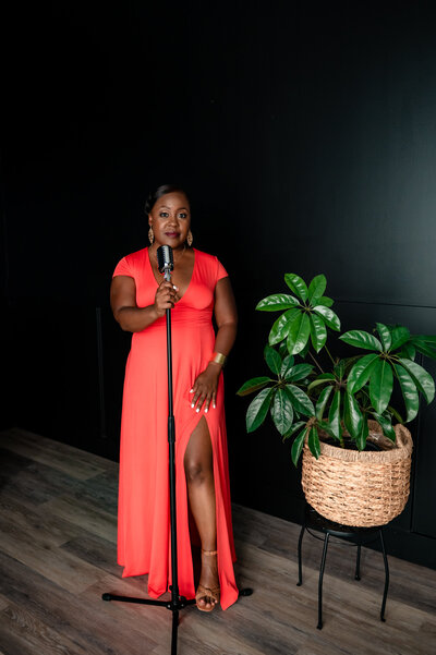 black female Jazz singer stands in front of a microphone wearing a bright peach dress Richmond VA