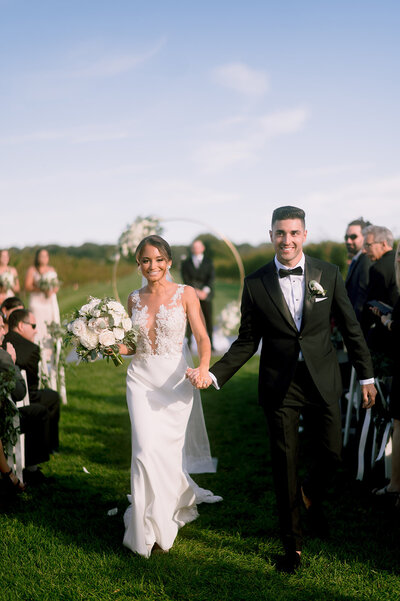 bride and groom walk down their ceremony aisle at their saltwater farm vineyard wedding  photo by cait fletcher photography