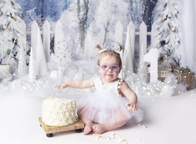 Little girl wearing white dress during cake smash photoshoot in Franklin Tennessee photography studio