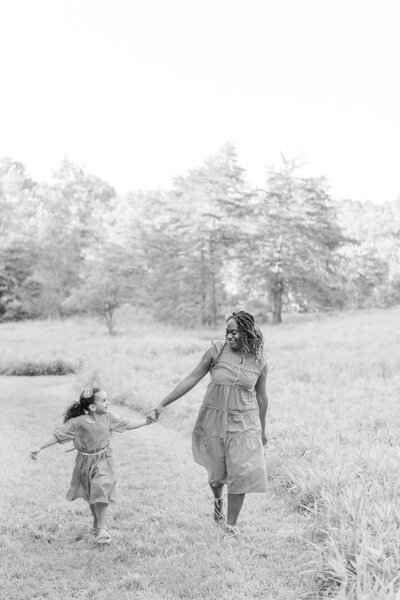 mom and daughter running while holding hands during spring minis in Oakton, Virginia