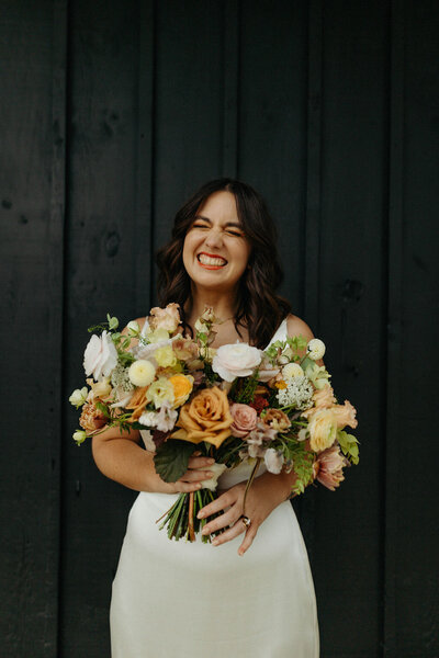 Bride with a big smile while holding bouquet - UME (New England Wedding Planner) were wedding vendor