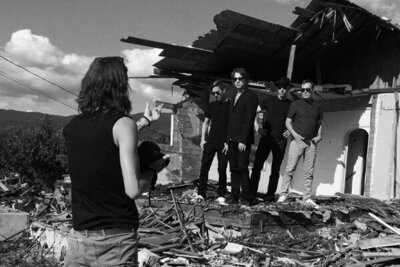 BTS photo black and white photographer Mark Maryanovich directing four members of 5440 standing in front of dilapidated building black and white image
