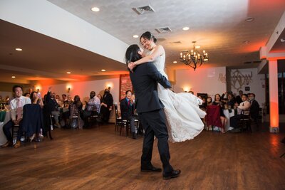 Groom lifting bride into the air at wedding reception