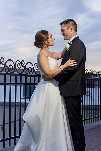Bride And Groom Hold Each Other Near Decorative Railing