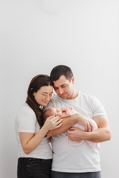mom and dad holding one of their twins during their home lifestyle session