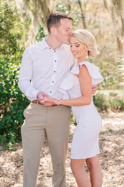 A husband kissing his wife's head in Raleigh by JoLynn Photography, a Raleigh wedding photographer