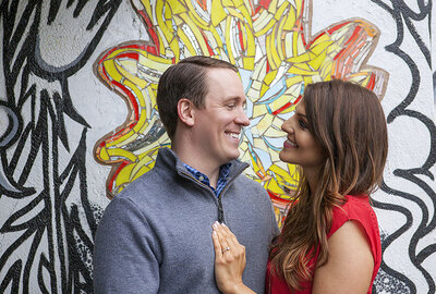 Engaged couple smiling at each other in front of Philadelphia mural