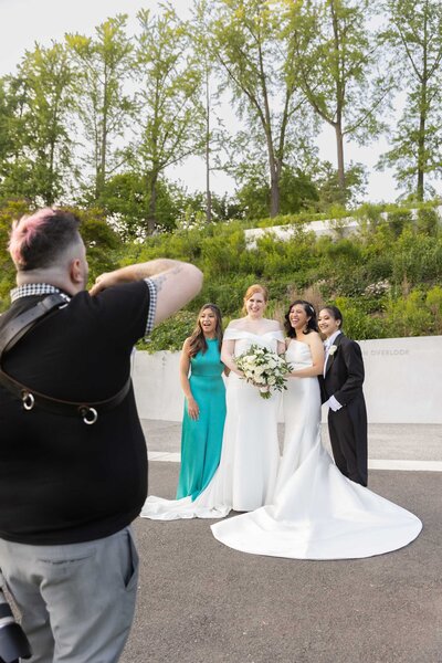 A photographer taking a picture of two brides and their bridesmaids.