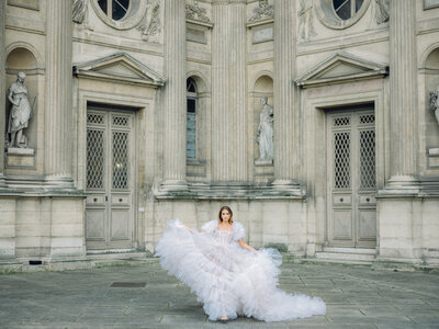 a woman in a large tulle dress walking towards the camera at the louvre