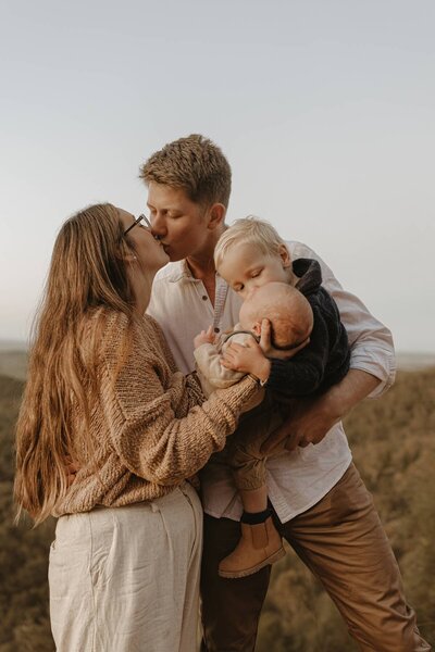 Family photographer capturing parents with their toddler and baby during a sunset photoshoot in Central West NSW.