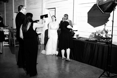 Black and white photo showing behind the scenes of a photographer and photo assistant lighting during a wedding day