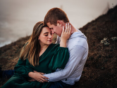 Family Photographer, a young couple hold each other on a hillside on a foggy day