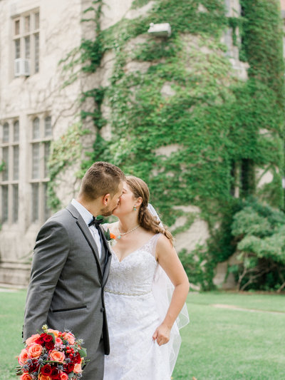 couple kissing in front of ivy lined building
