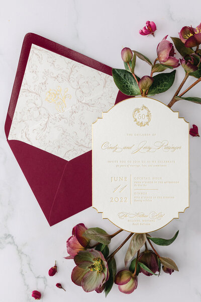 Gold foil 50th wedding anniversary invitation featuring a blush and gold foil envelope liner with a burgundy envelope.