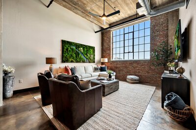 Living room with ample seating, exposed brick and natural light  in this 3-bedroom, 2-bathroom luxury condo in downtown Waco, TX