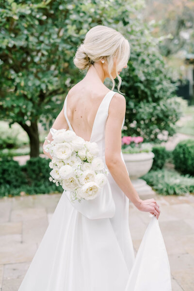 Beautiful blonde bride holds her skirt and wedding bouquet at the River Oaks Garden Club