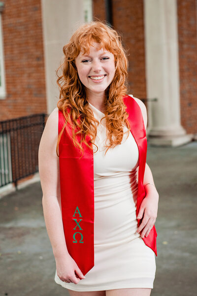 Alpha Chi Omega Senior wearing a red stole and smiling at the camera