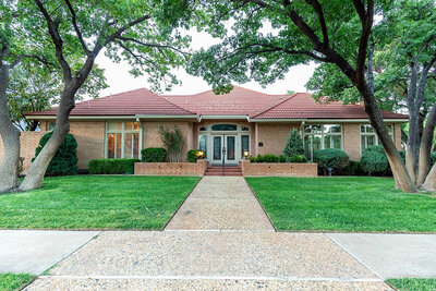Exterior photo of house in Lakeridge with large oak trees in yard in Lubbock TX