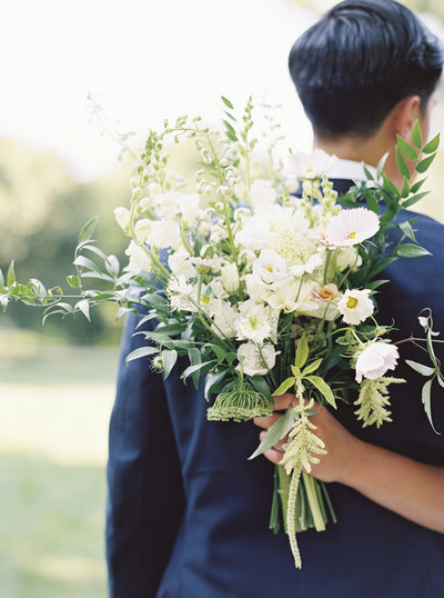 Bride hugging groom with wedding flowers