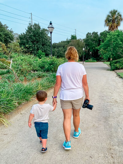 Family photographer in Charleston SC walking with a little boy and holding his hand at Hampton Park Charleston SC