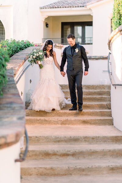 Bride and Groom walking down the stairs holding hands at the Omni Montelucia