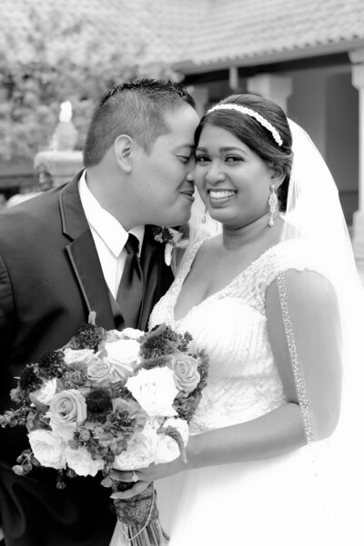 Groom nuzzling bride's cheek while bride smiles.