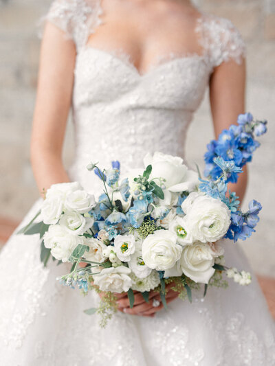 Close up of bride's hands holding her white and blue bouquet