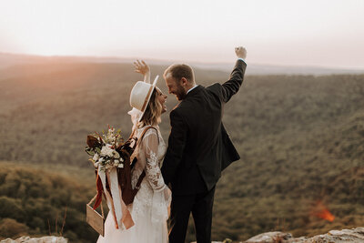 Bride and groom throwing hands up in celebration during their elopement in the mountains