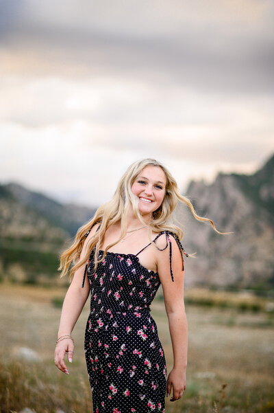 Littleton Senior Photographer captures a girl with long blonde curls twirling around in front of the colorado mountains