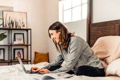 Woman working on laptop in bed learning how to build a website on Showit