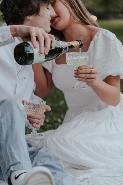 couple pouring champagne celebrating their engagement on the jersey shore