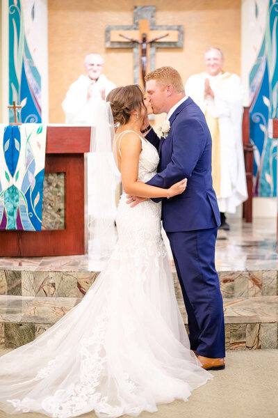 Bride and groom embrace in first kiss while inside catholic church in grand island, nebraska