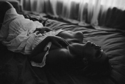 black and white image  woman laying on bed posing