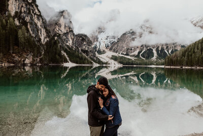 Couple's post-proposal hug at Lake Braies, Dolomiti mountains. Breathtaking scenery and raw emotions captured by my photography services, specializing in couples and elopements