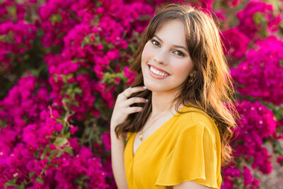 high school senior girl smiling in front of flowers
