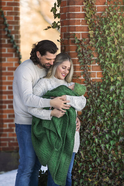 Mom and Dad hold newborn baby outside for photos at studio in mount holly, New Jersey.