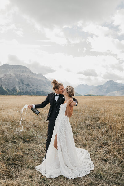 Couple kissing and popping champagne in the mountains of Alberta, Featured on the Bronte Bride Blog.
