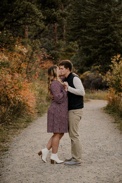 Engaged couple kisses with a mountain backdrop