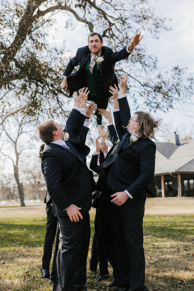 groom being tossed up in the air by groomsmen