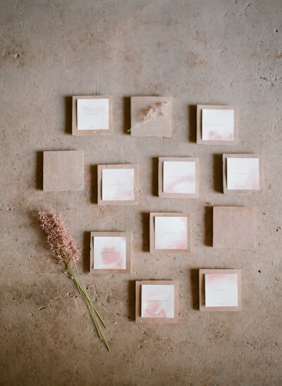 Post-it stamp-sized paper placed in wooden squares beside a flower cut.