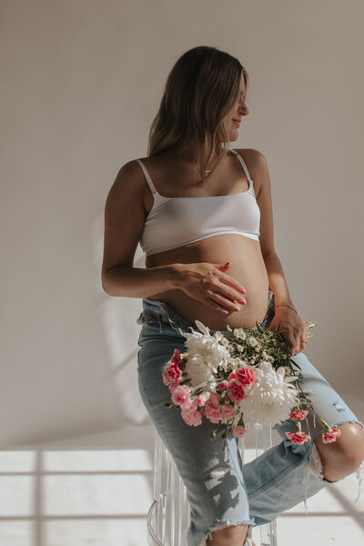studio maternity session in kcmo made extra special with flowers and denim jeans with white bra. Studio window light made it look like film