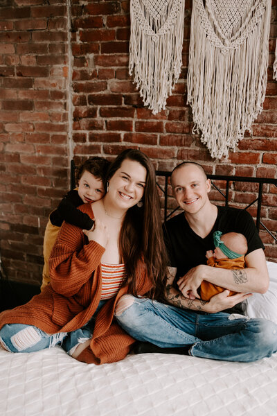 family with toddler and newborn smiling at the camera