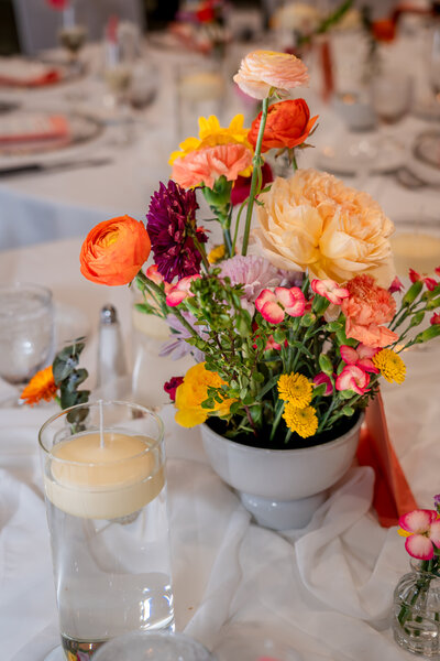 Colorful floral centerpiece with orange and pink roses in white vase – photographed by wedding photographer Niko Coric – Lumen Clarity Media