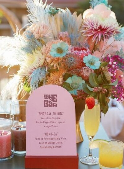 Close up of a groovy and retro floral centerpiece and drink menu for a retro grateful dead themed wedding