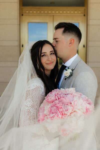 Newly married couple with pink peonies bridal bouquet.