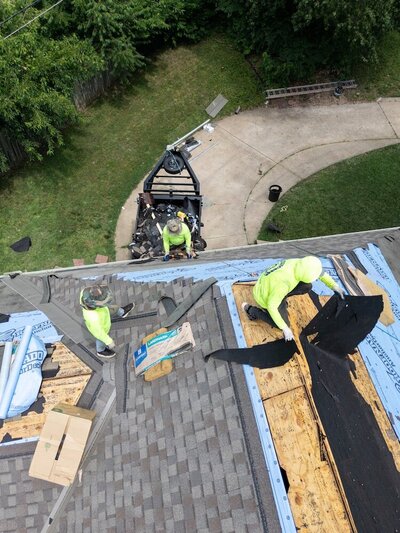 Three men working on replacing a Kanas City roof with new shingles